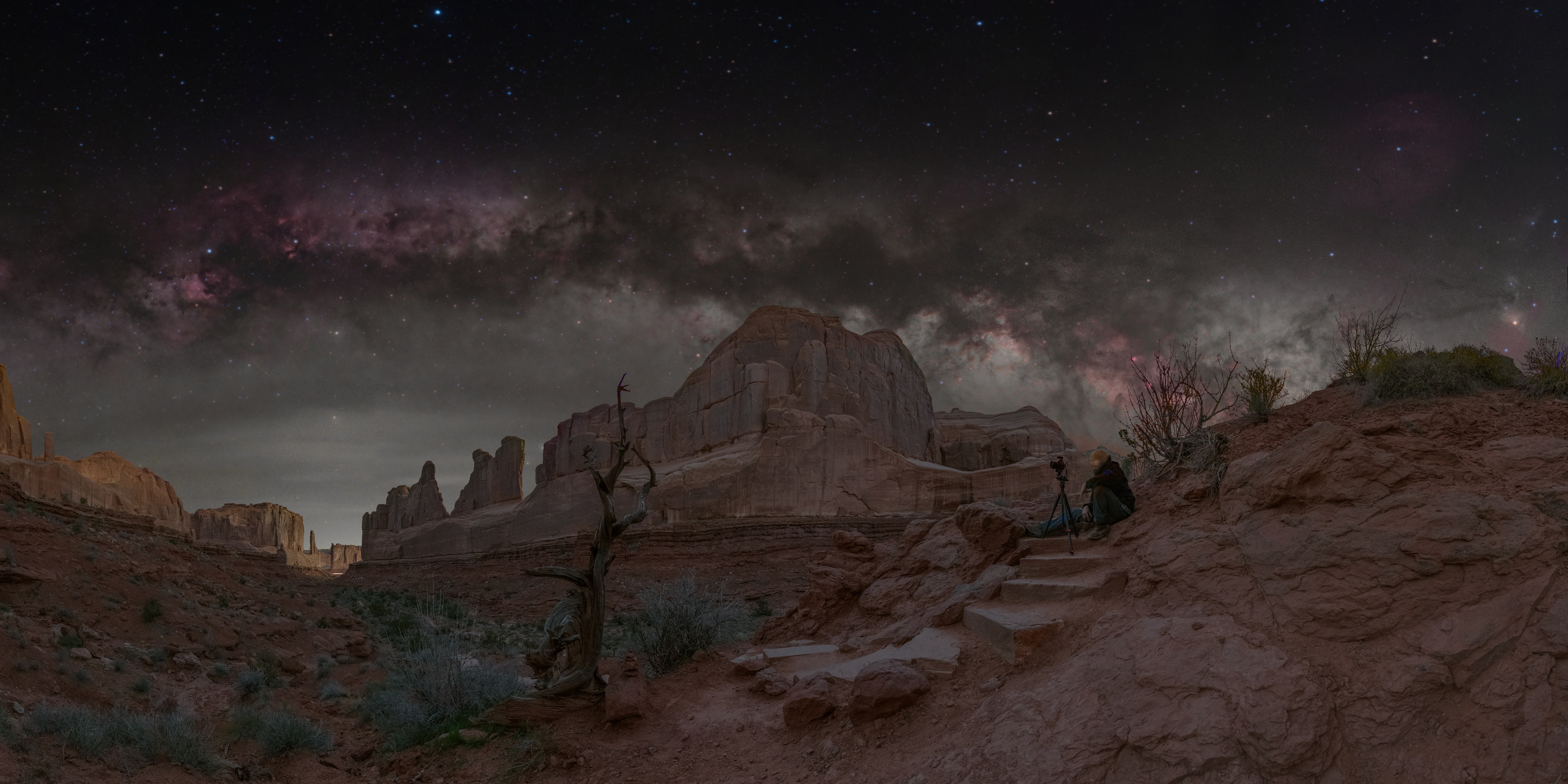 The Milky Way and Cygnus above Park Avenue’s sandstone formations, with a photographer seated beside a camera on the steps